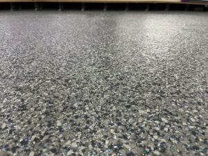 Close-up of custom purple glitter epoxy topcoat on anti-slip VOC-approved cheerleading gym floor by GonzaBuilt in Kendall, Florida