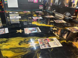 Detail view of Hollywood-style star and newspaper print elements embedded in custom gold metallic epoxy museum floor after GonzaBuilt handmade installation in Miami, Florida